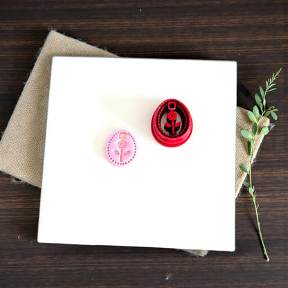 floral oval charm next to red cutter on white tile