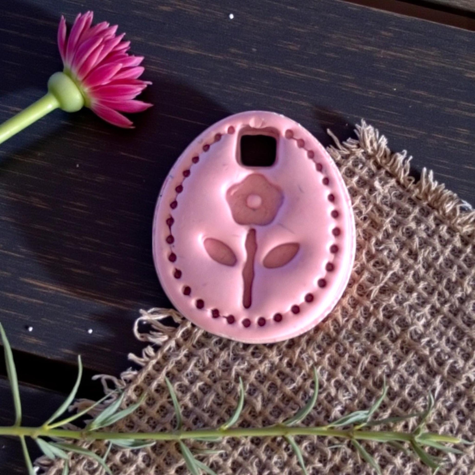 closeup pink floral oval clay charm on burlap