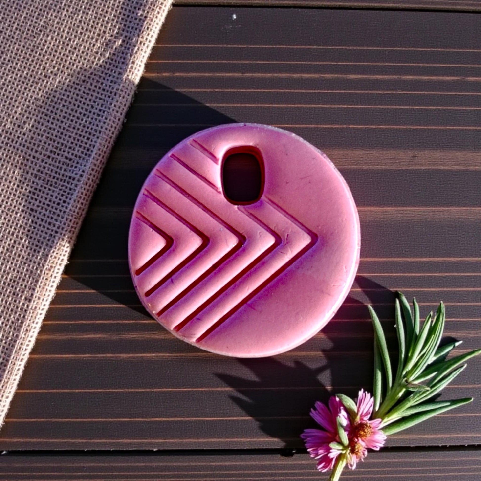 round charm with chevron lines in sunlight on wooden board
