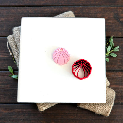 pink seashell charm next to red cutter tool