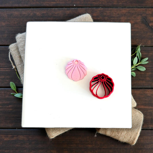 pink seashell charm next to red cutter tool