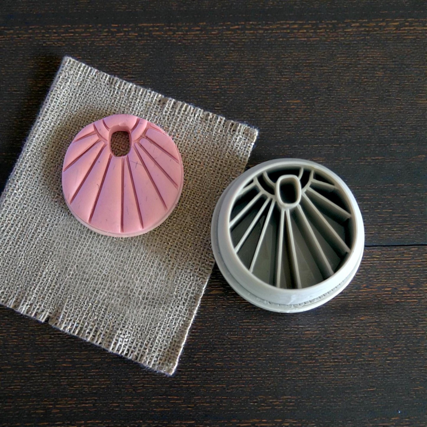 Sunburst charm next to gray cutter on burlap