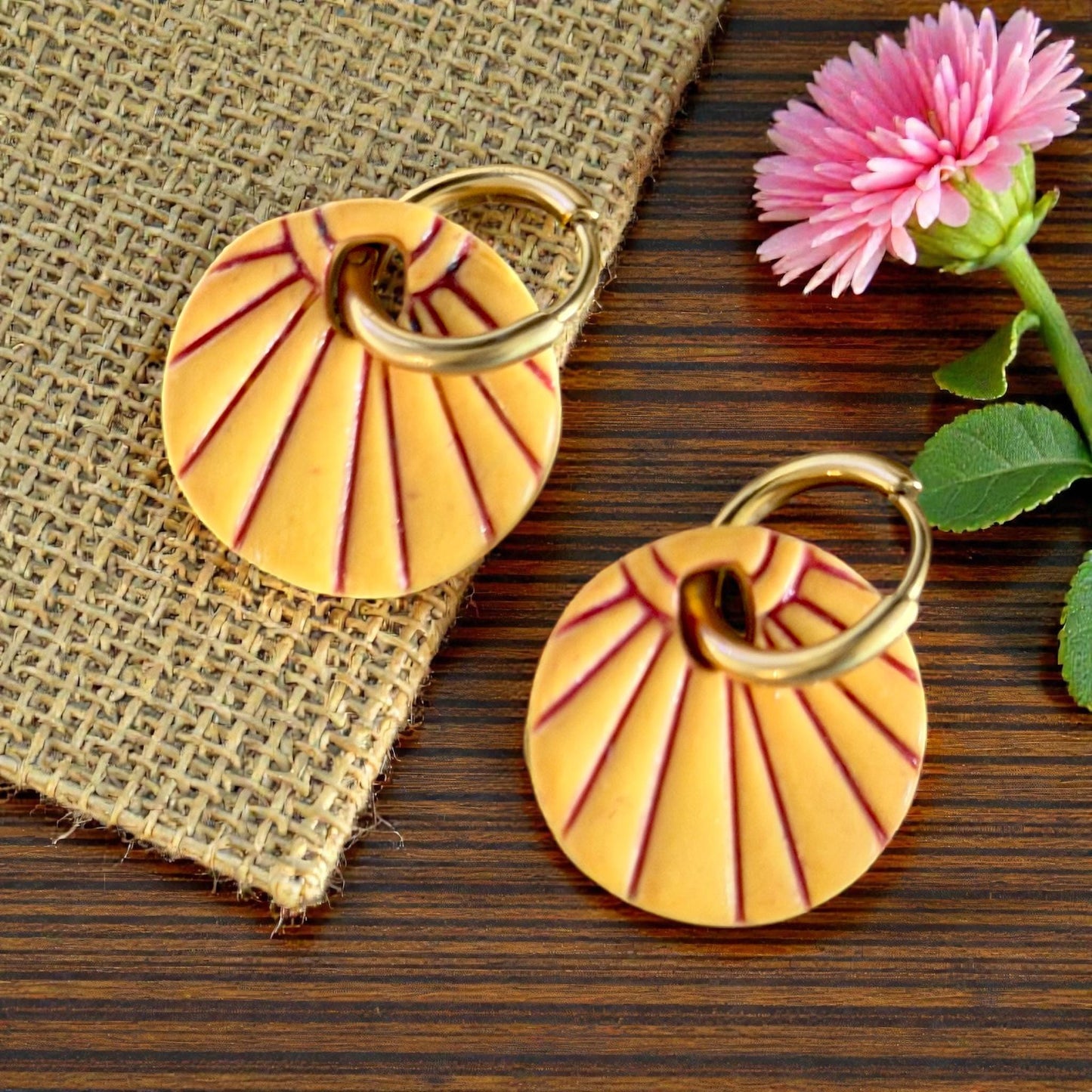 Close-up orange sunburst earrings with flower