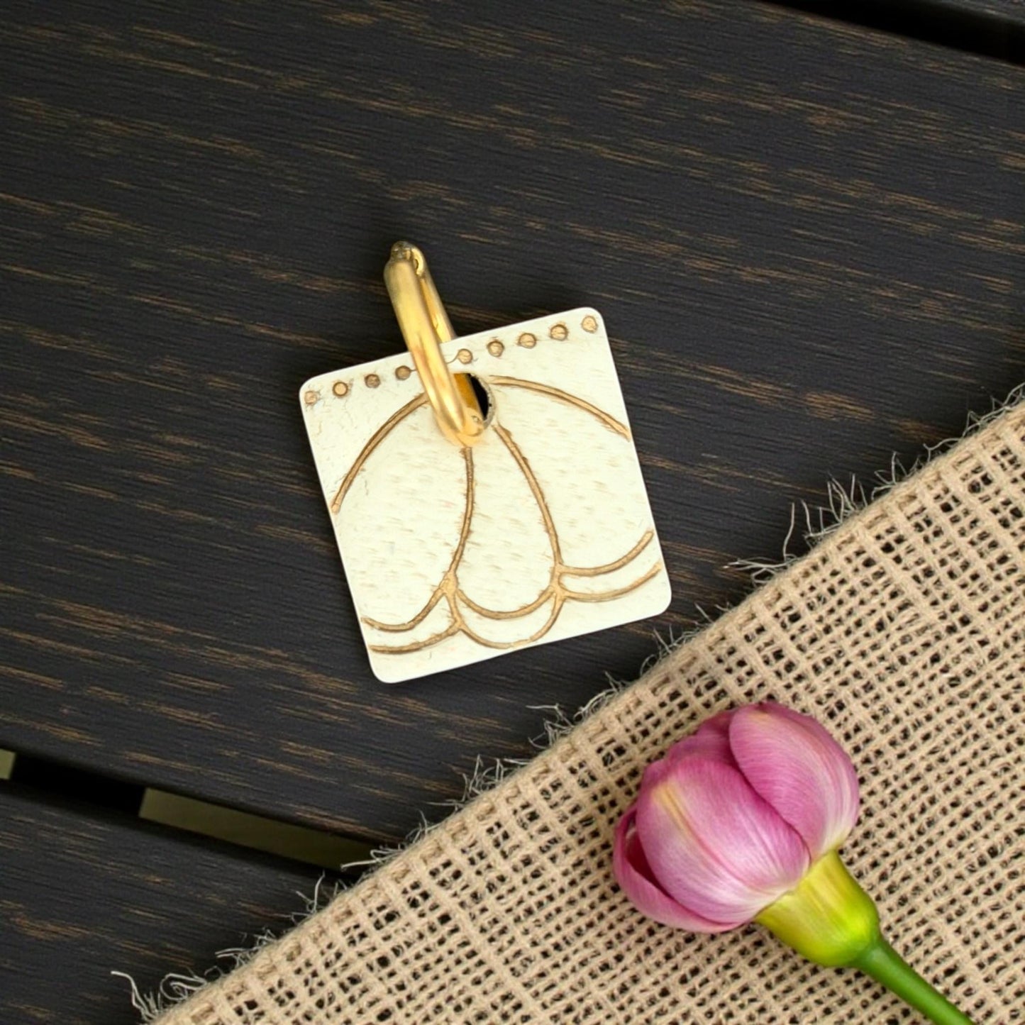 gold metal charm engraved with petal design
