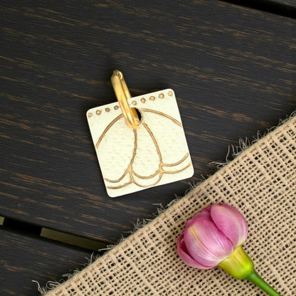 gold metal charm engraved with petal design