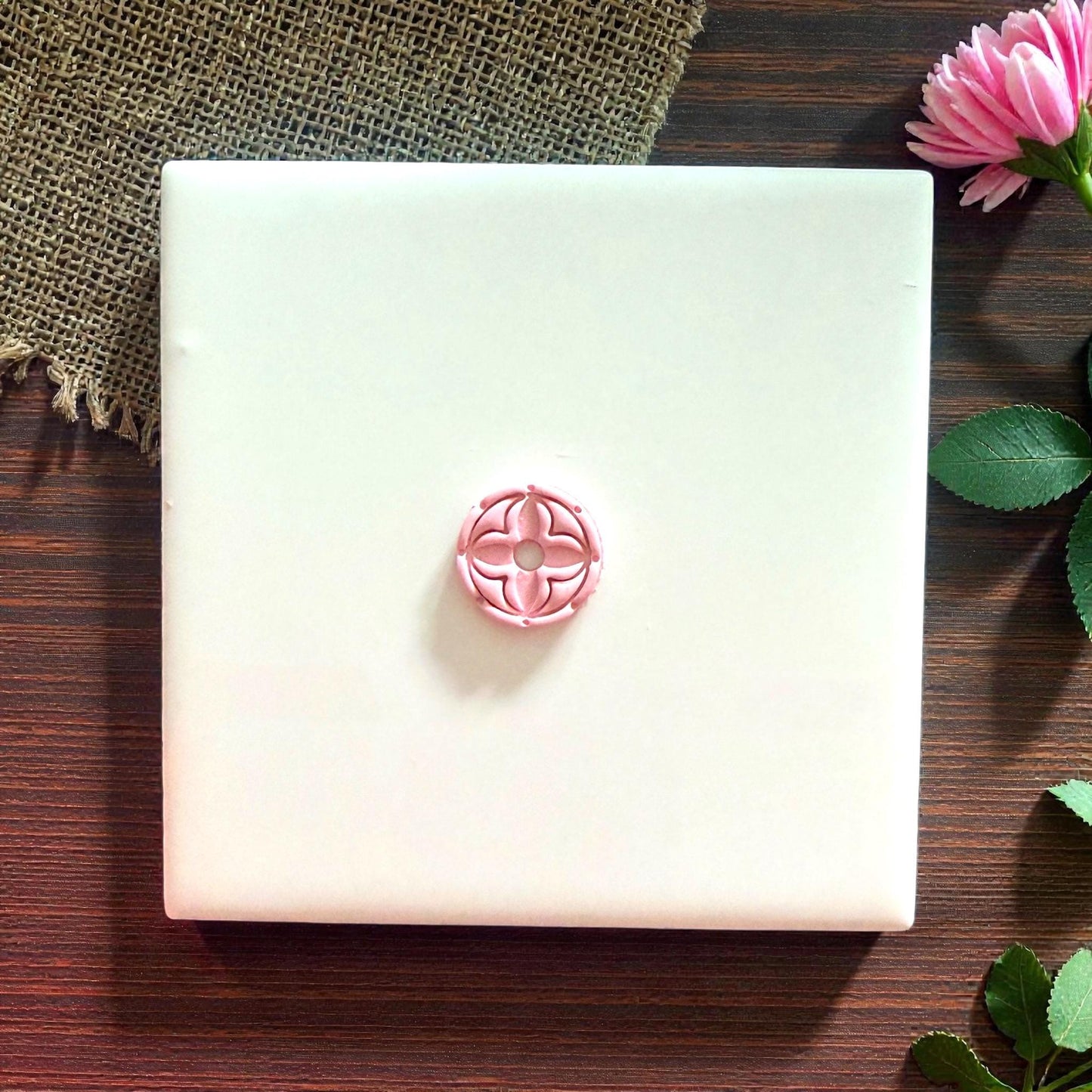 pink round quatrefoil clay impression on burlap