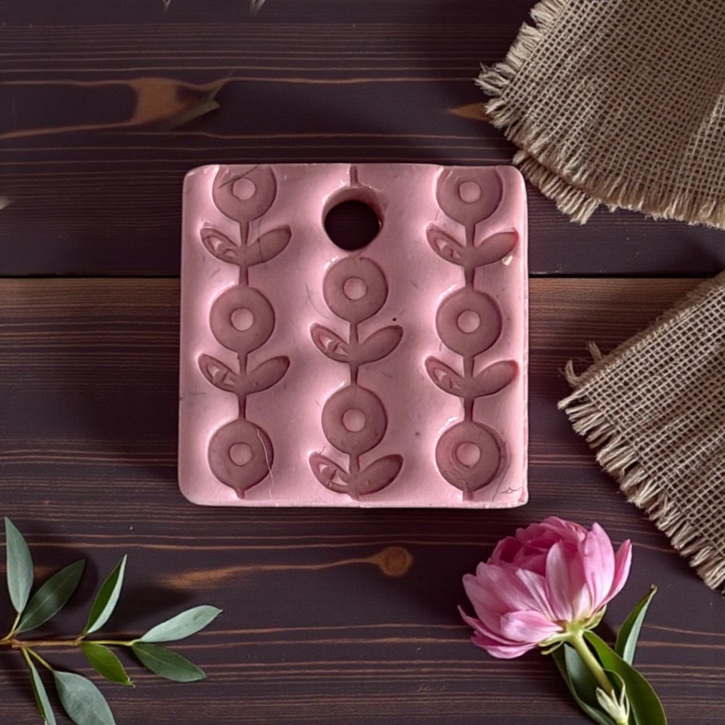 pink embossed floral clay charm on wood background