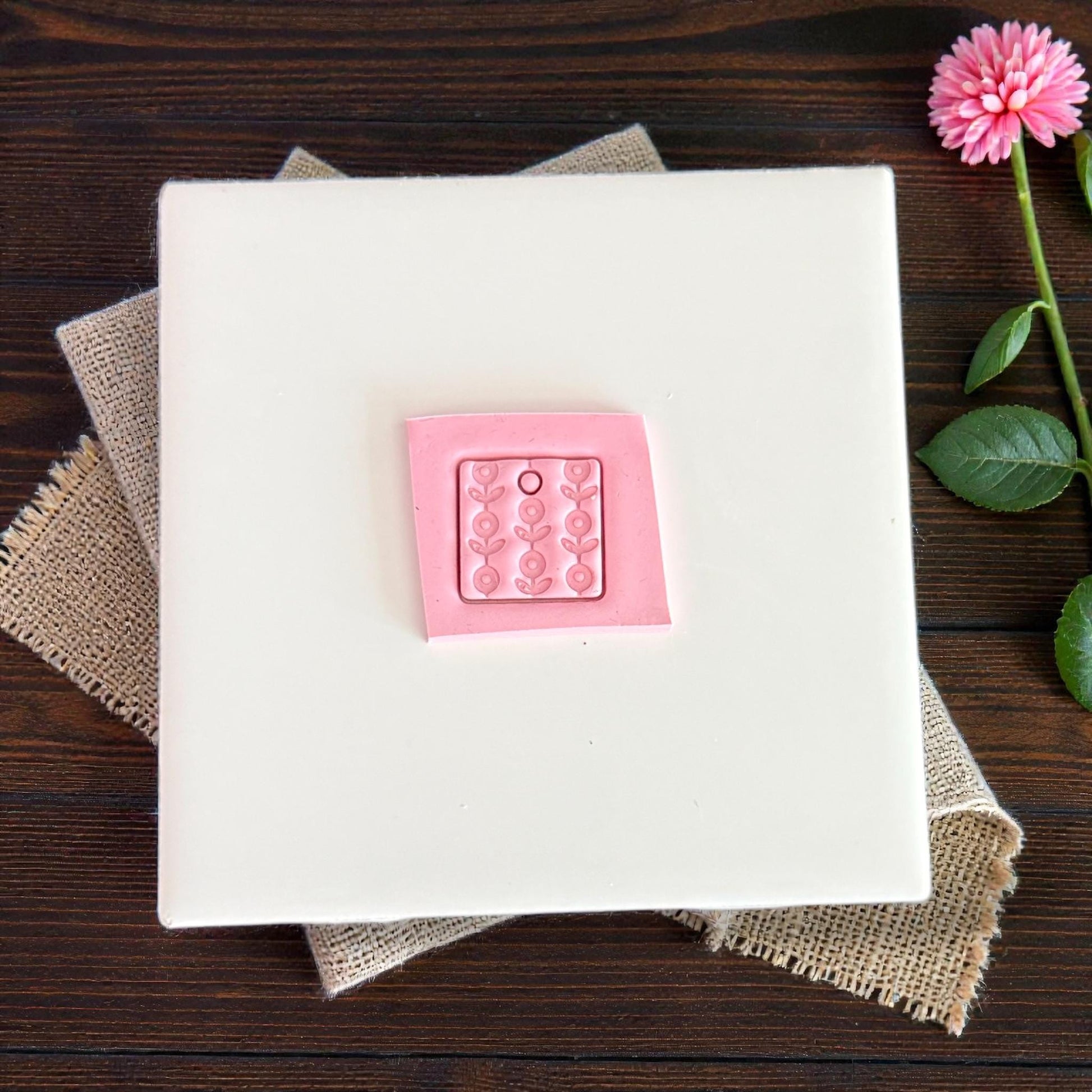 pink floral square clay charm on white tile
