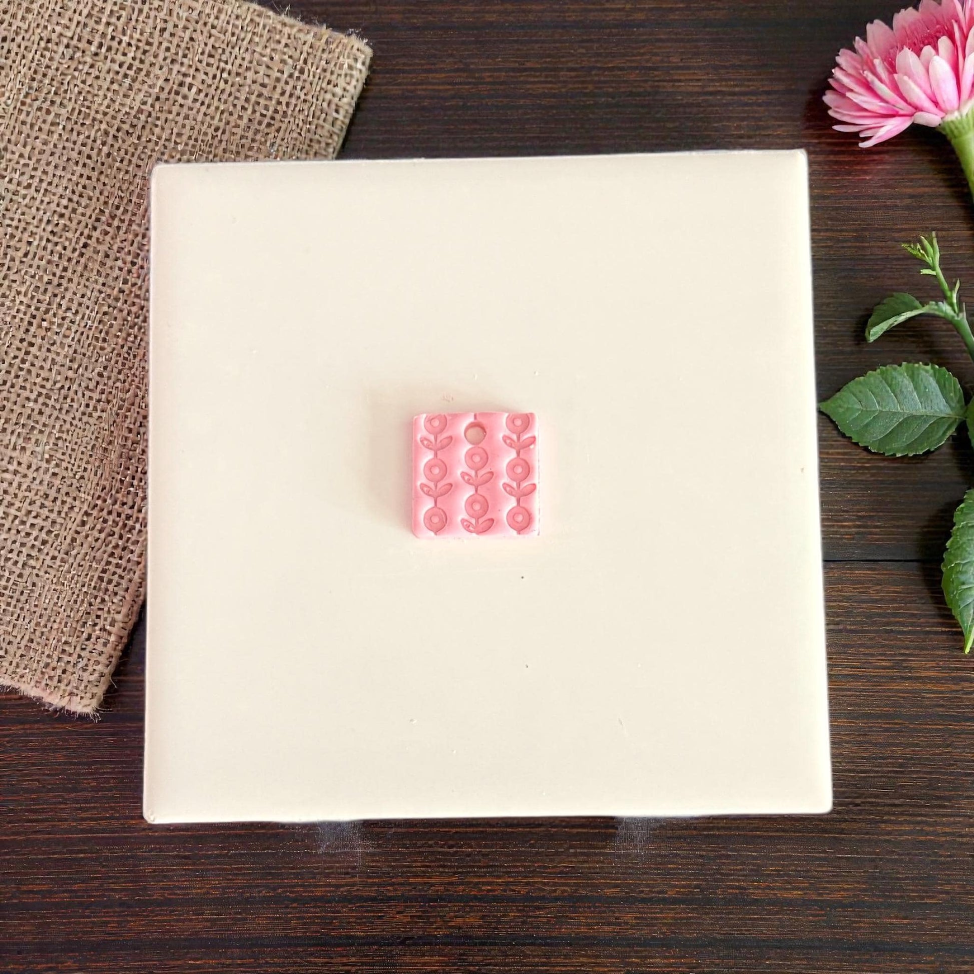 close-up pink floral clay charm on white tile