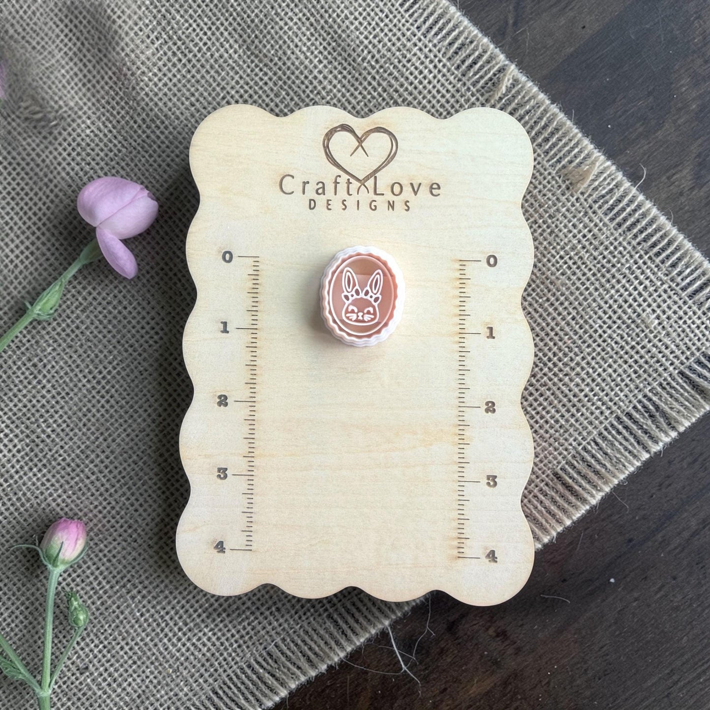 bunny clay imprint beside oval cutter on burlap with flower