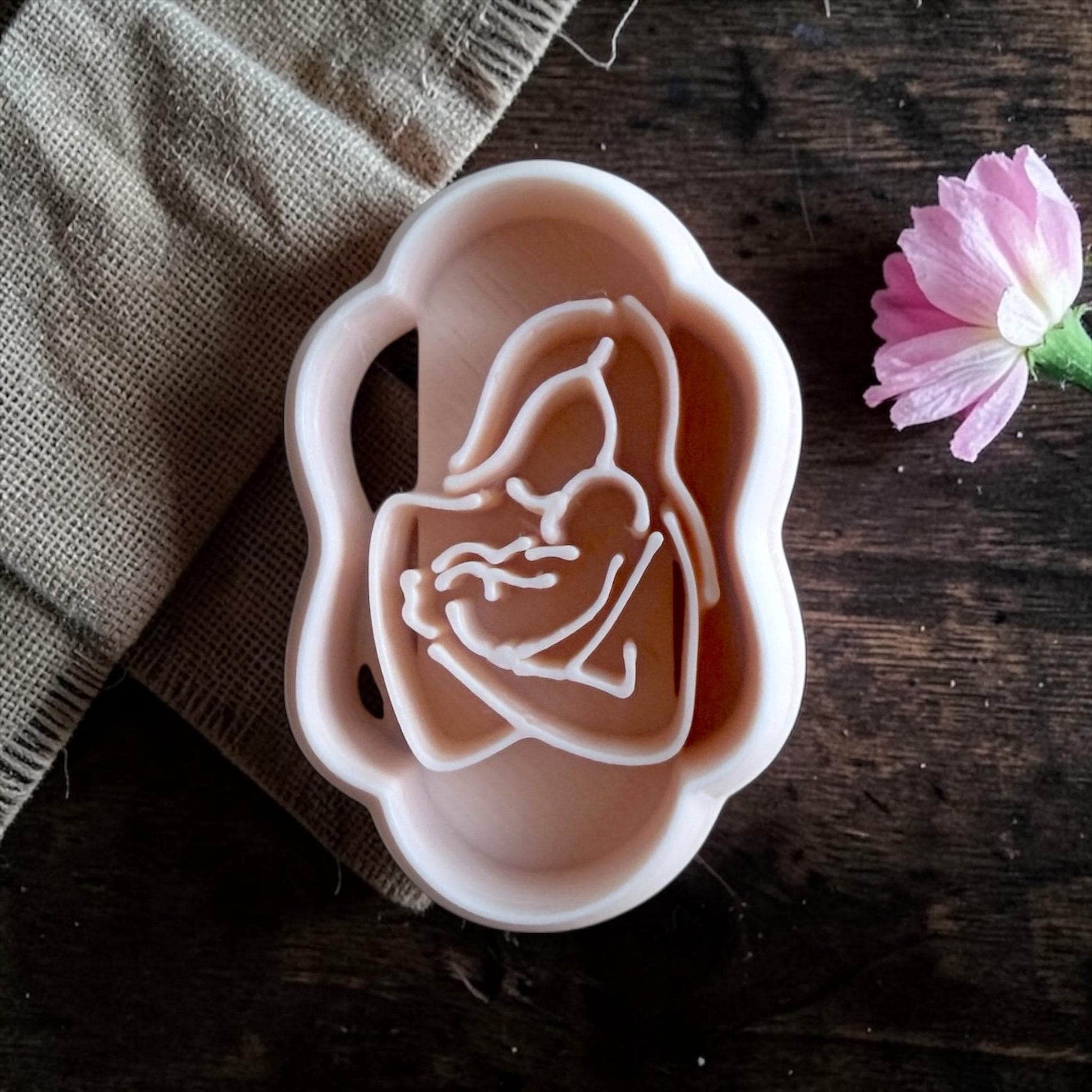 Mother and baby silhouette polymer clay cutter closeup on dark wood with pink flower