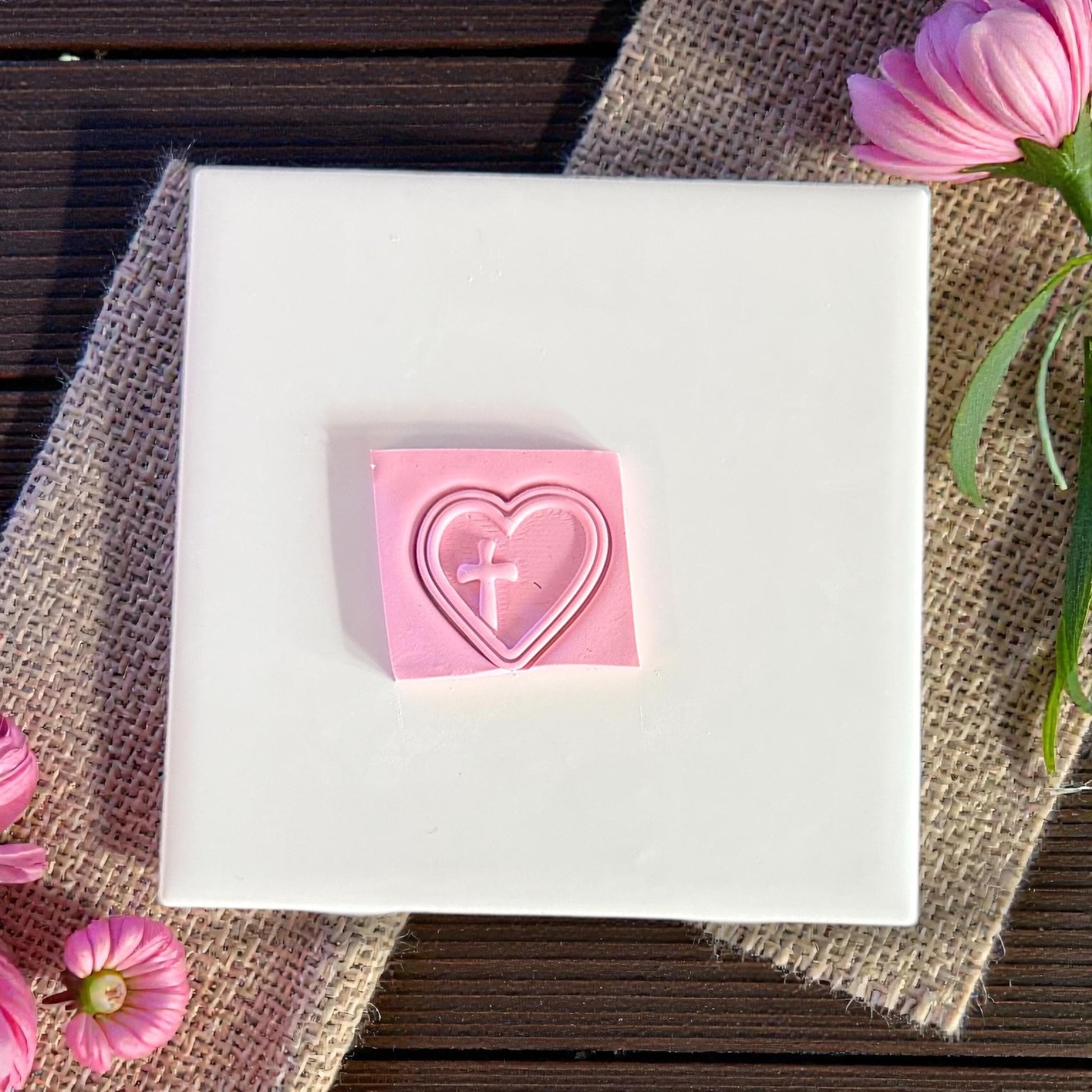 heart cross clay imprint on pink clay square