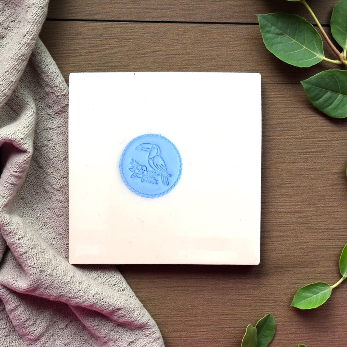 small blue toucan clay stamp displayed on white tile