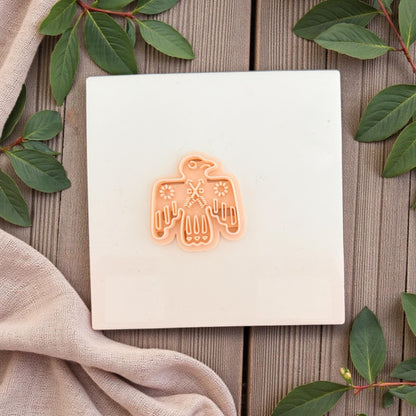 small folk bird cutter centered on white tile