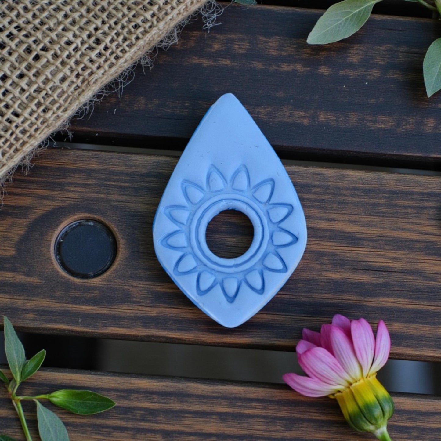 blue clay impression of sunburst teardrop cutter on wood background