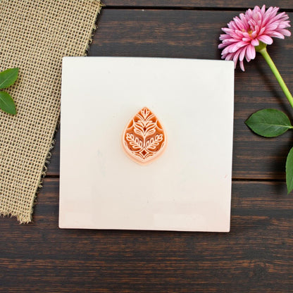 Small teardrop leaf pattern clay cutter displayed on ceramic tile