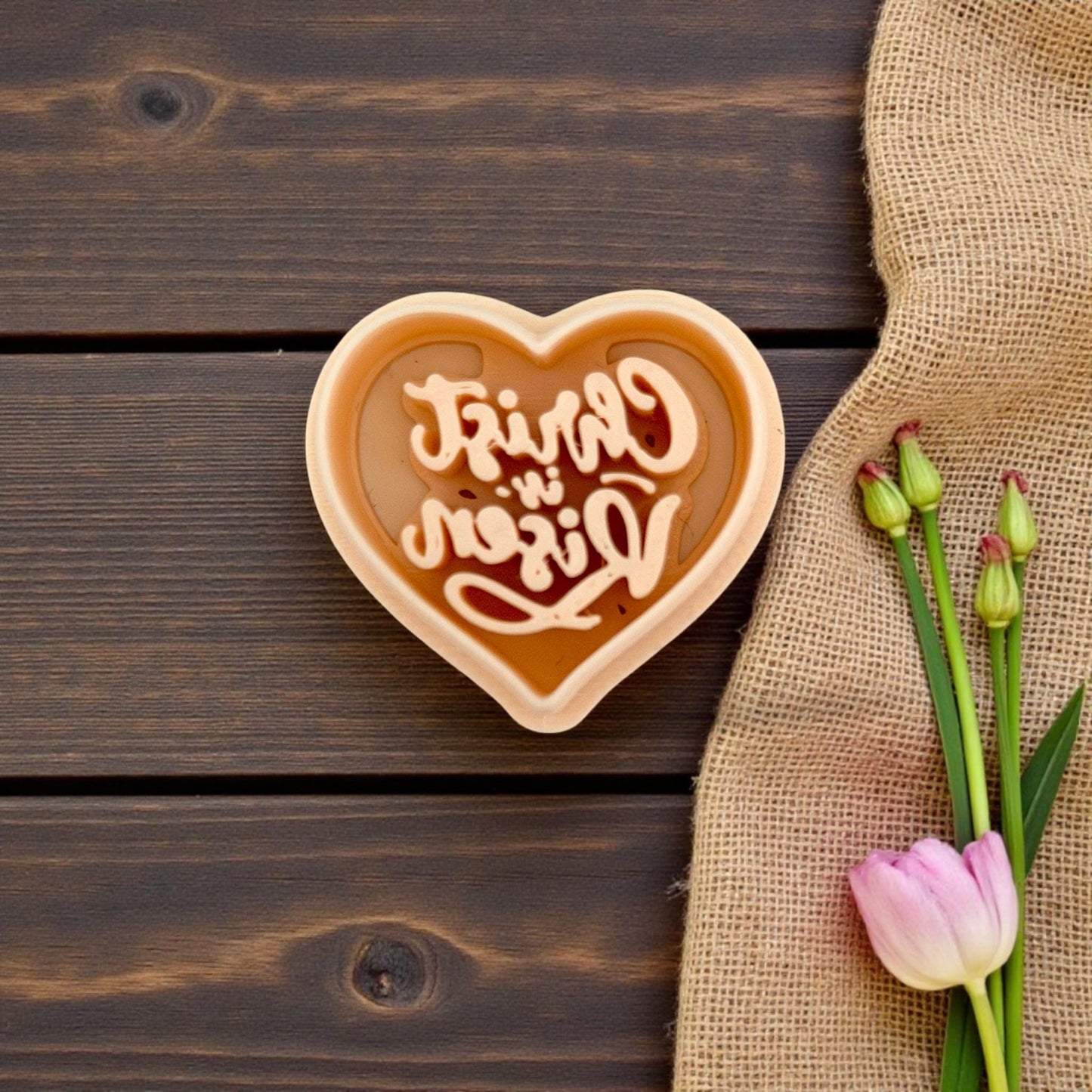 Heart cutter filled with clay on wood background and tulip