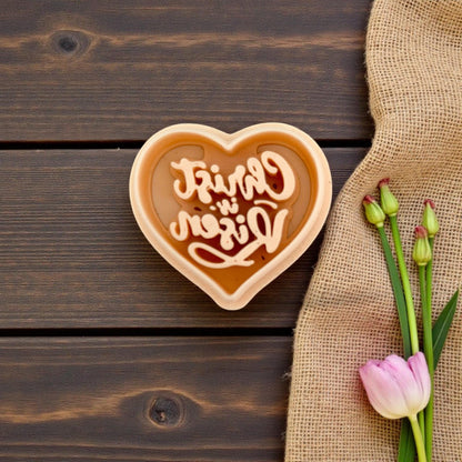 Heart cutter filled with clay on wood background and tulip