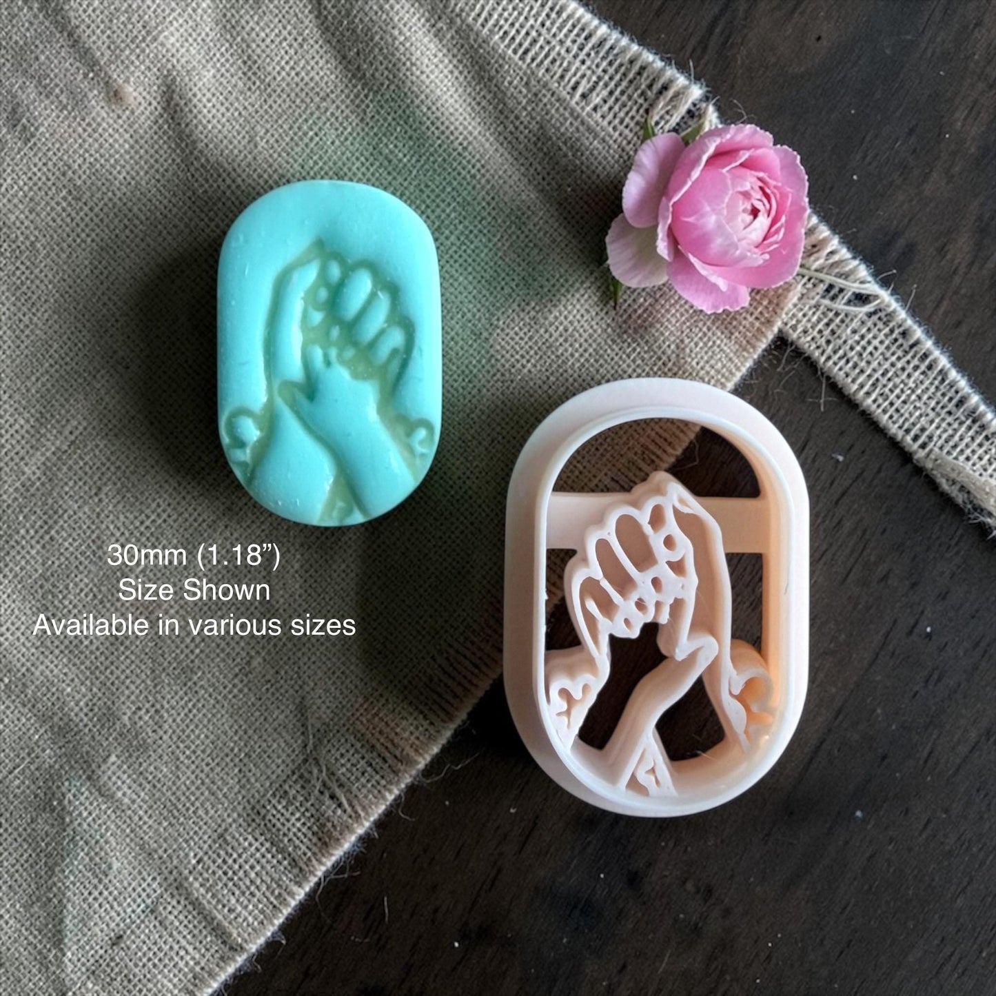 mother holding baby hand polymer clay cutter with finished clay example