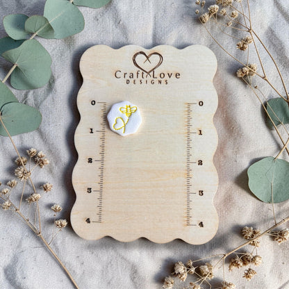 yellow bee stamped clay example on measuring board