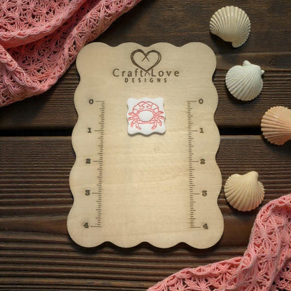 crab imprint displayed on wooden size board with shells and pink fabric