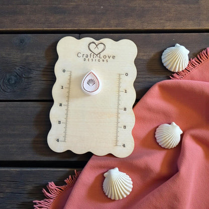 teardrop seashell imprint on wooden surface with pink cloth