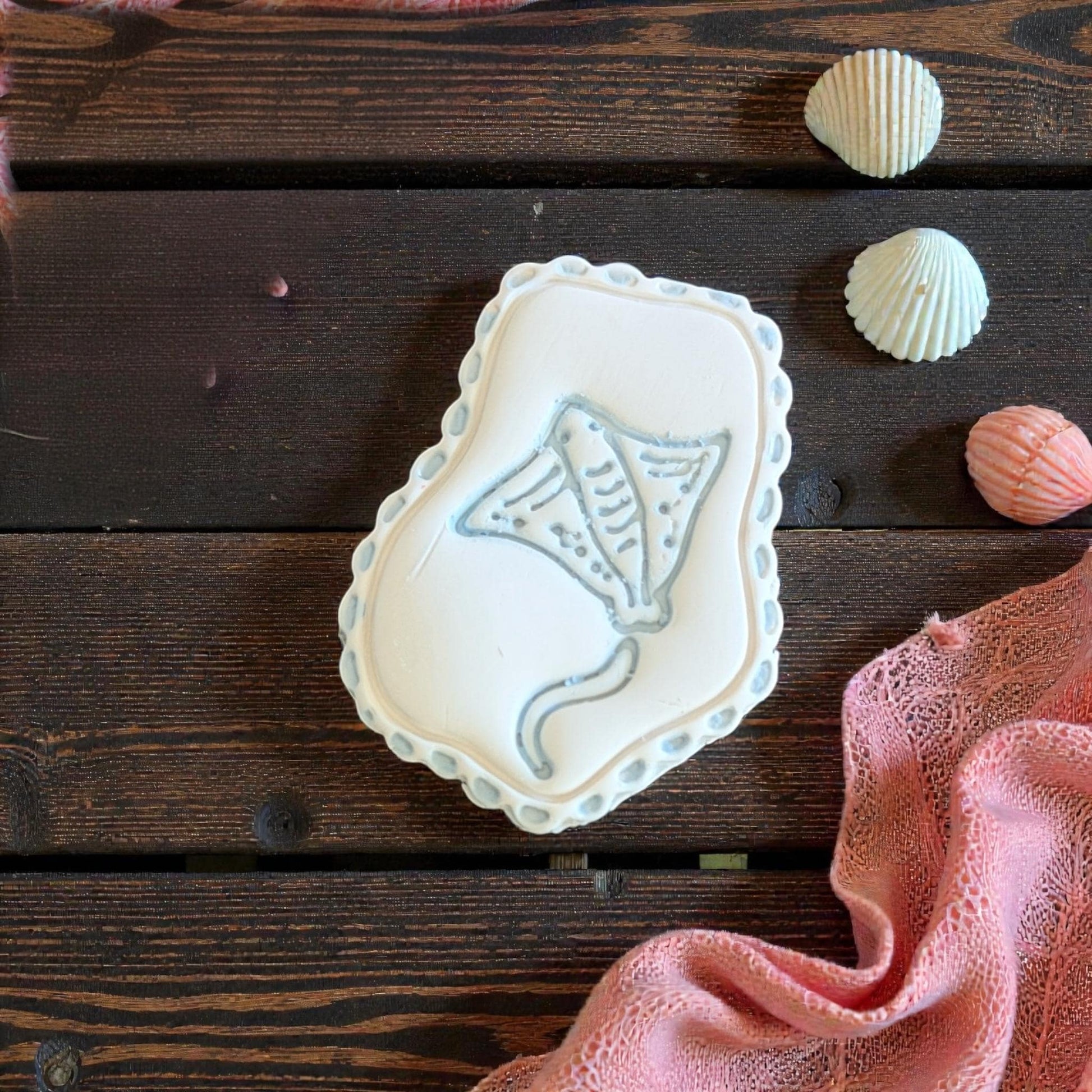 manta ray clay imprint with scalloped frame on wood