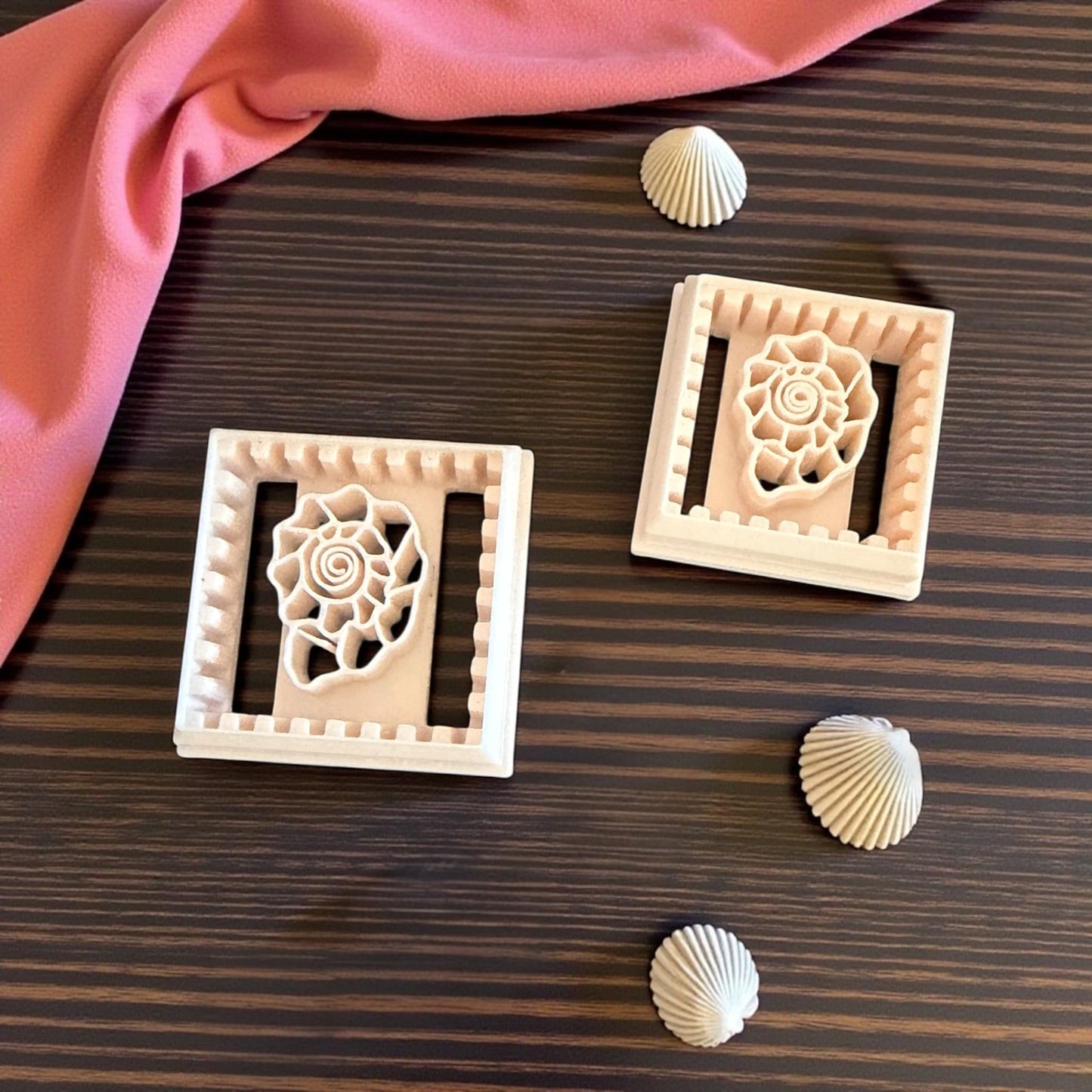 two square shell tile cutters with scalloped borders on wood background and shells