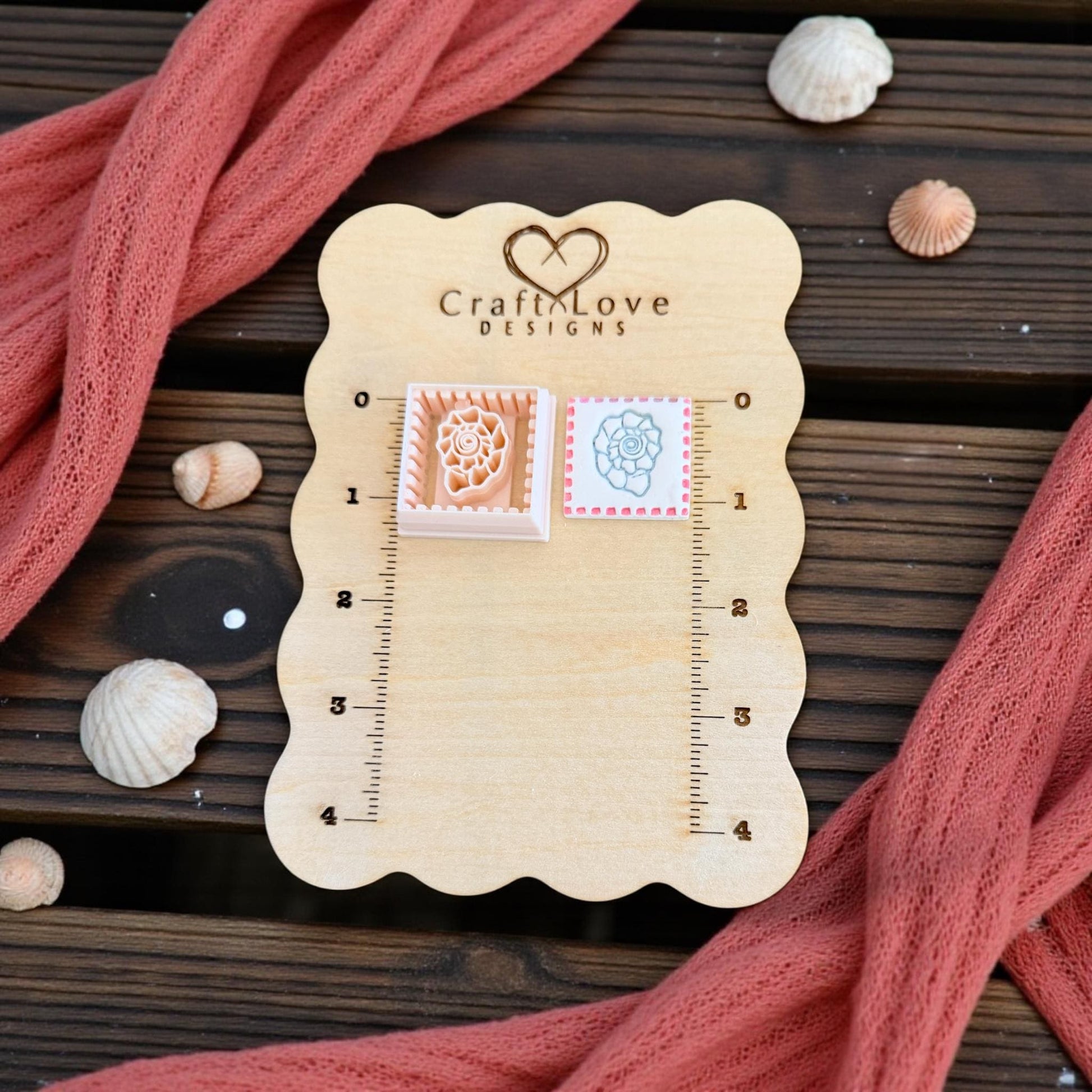 two shell tile pieces shown on wooden board with shells and pink fabric