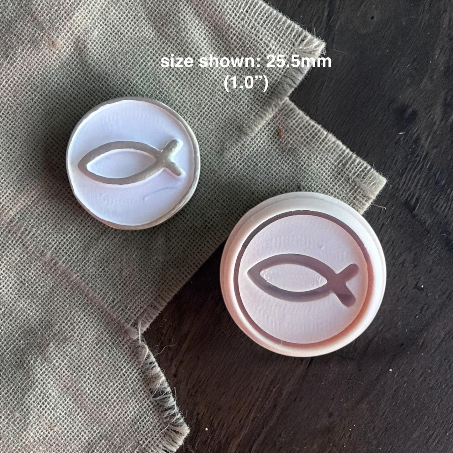 Close-up of round polymer clay cutter with debossed Christian fish symbol on clay