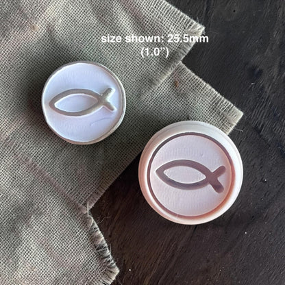 Close-up of round polymer clay cutter with debossed Christian fish symbol on clay