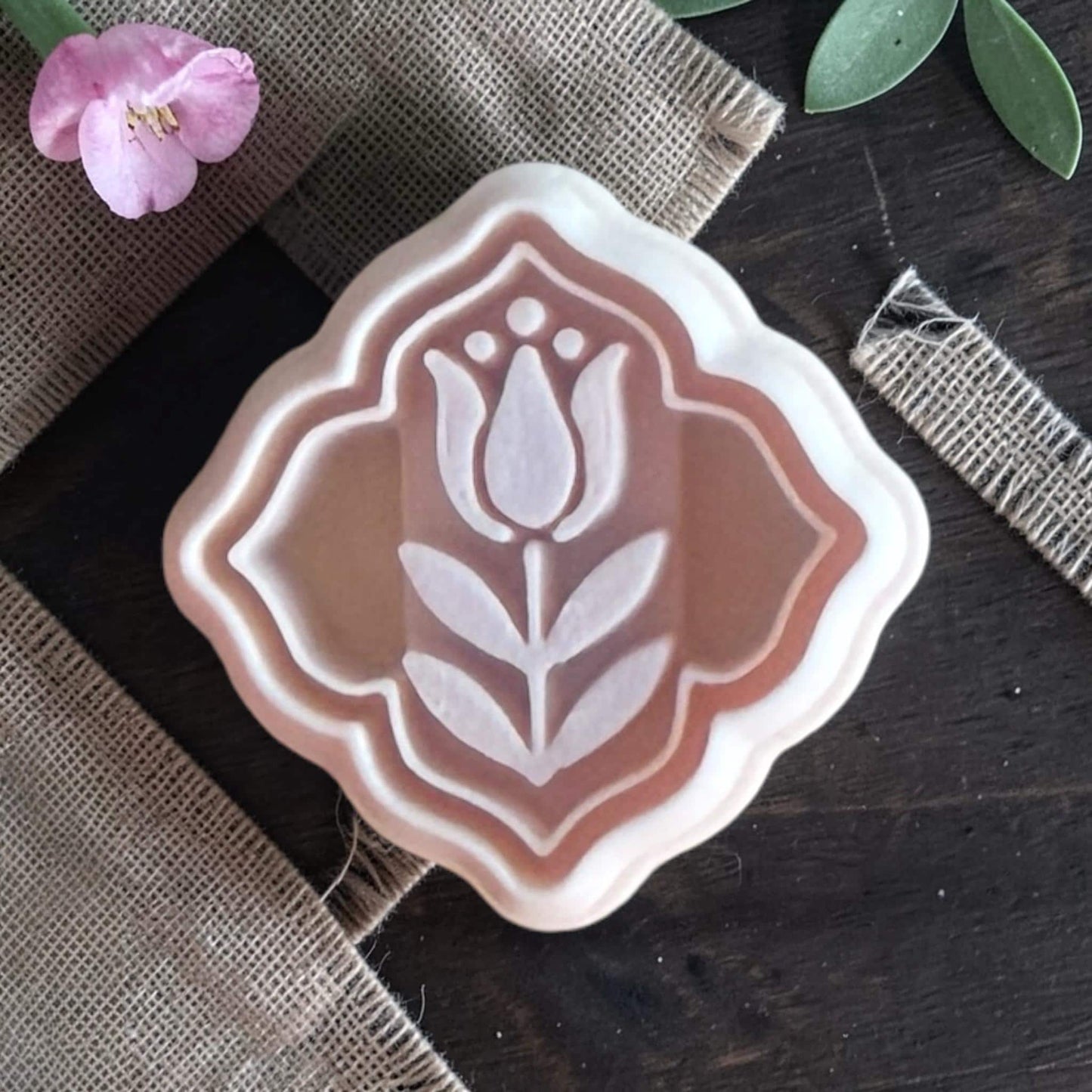 Polymer clay cutter with folk tulip design inside decorative frame on burlap fabric