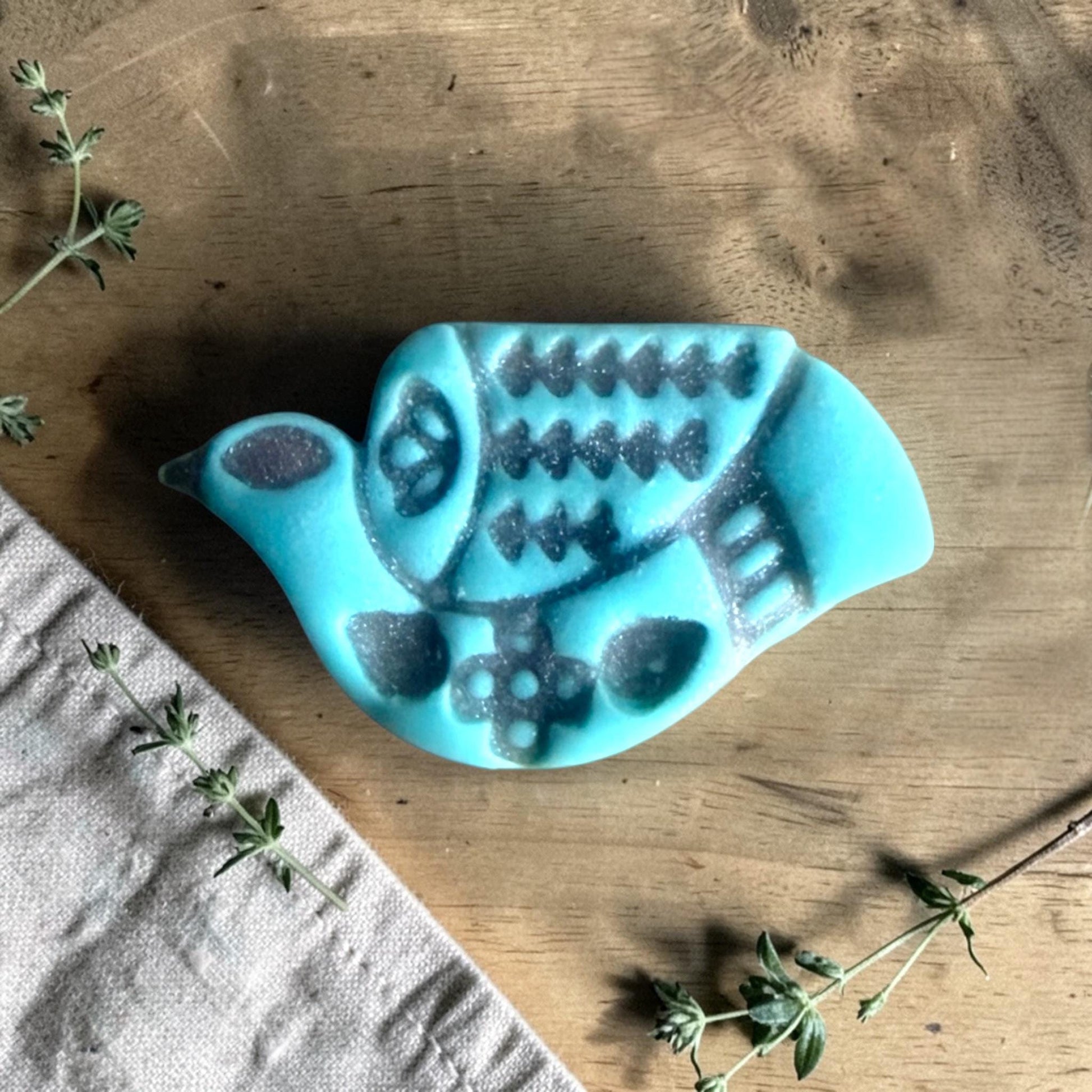 turquoise clay folk bird charm with embossed Scandinavian pattern on wood surface