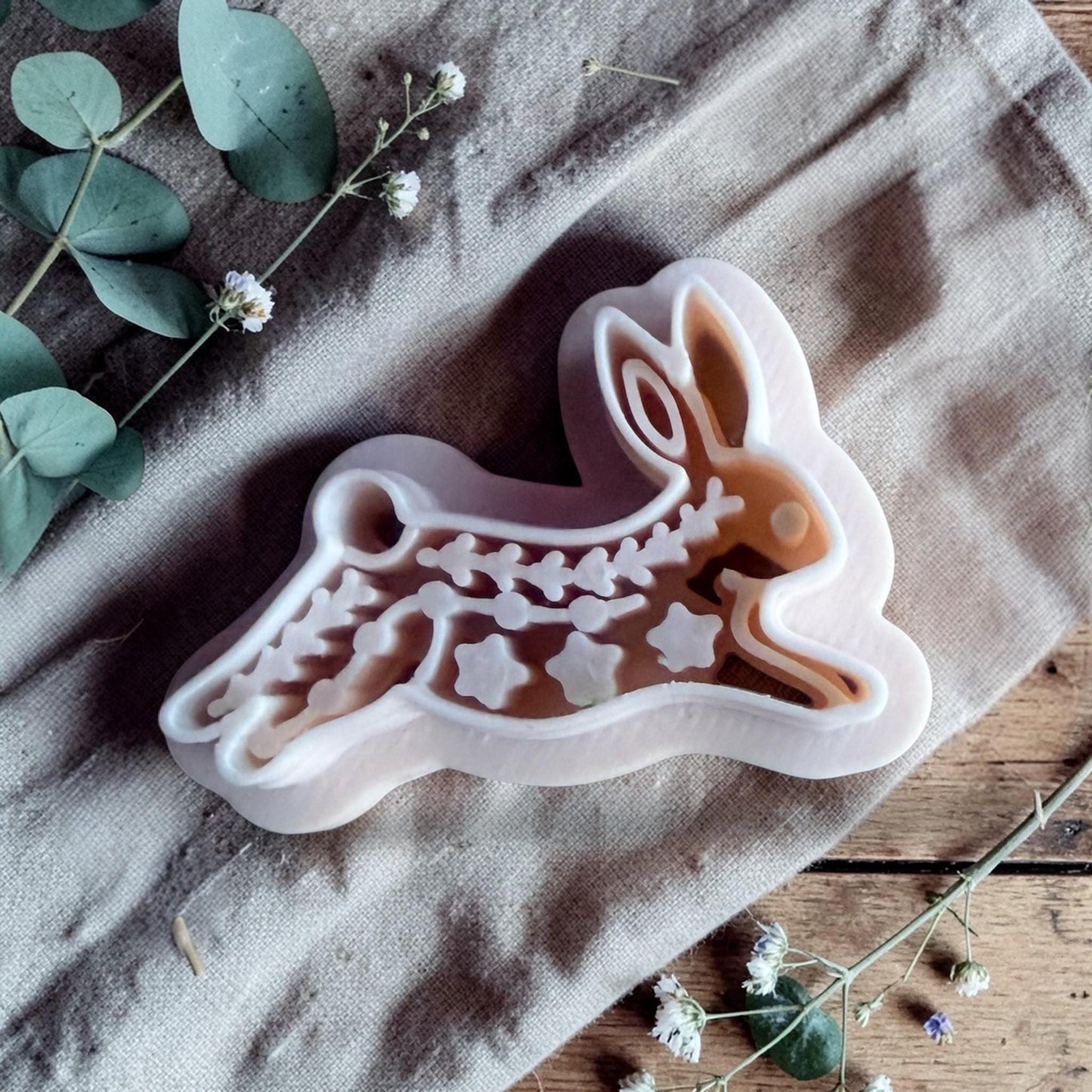 white polymer clay rabbit cutter with embossed folk art pattern on fabric background