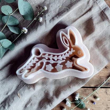 white polymer clay rabbit cutter with embossed folk art pattern on fabric background