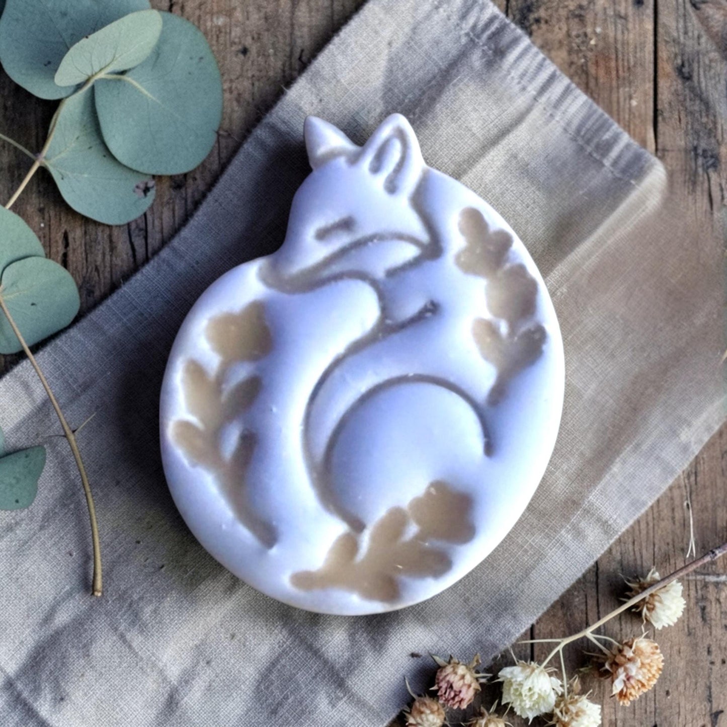 finished clay fox charm with embossed floral details on linen background