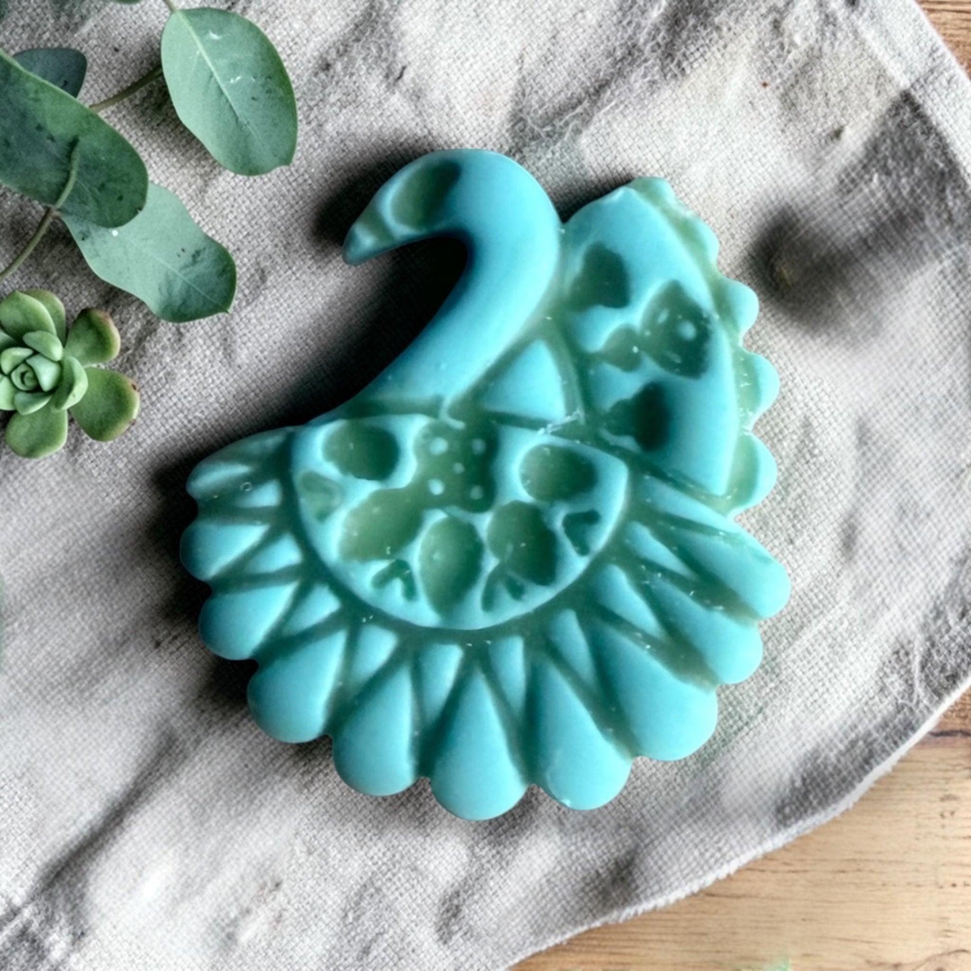 turquoise clay peacock charm with embossed folk art pattern on linen fabric