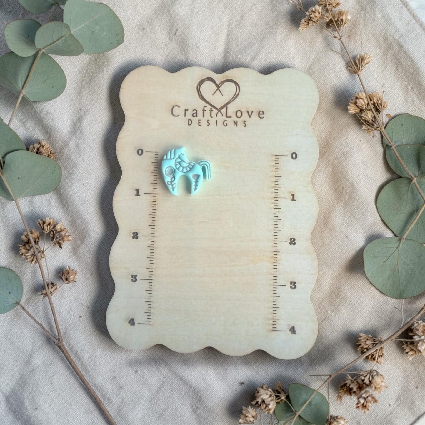 finished turquoise clay horse charm displayed on Craft Love Designs ruler board