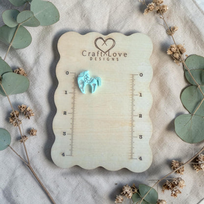 finished turquoise clay horse charm displayed on Craft Love Designs ruler board