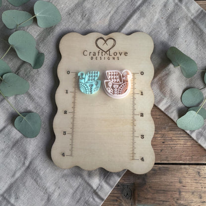two finished clay bird charms displayed on Craft Love Designs ruler board