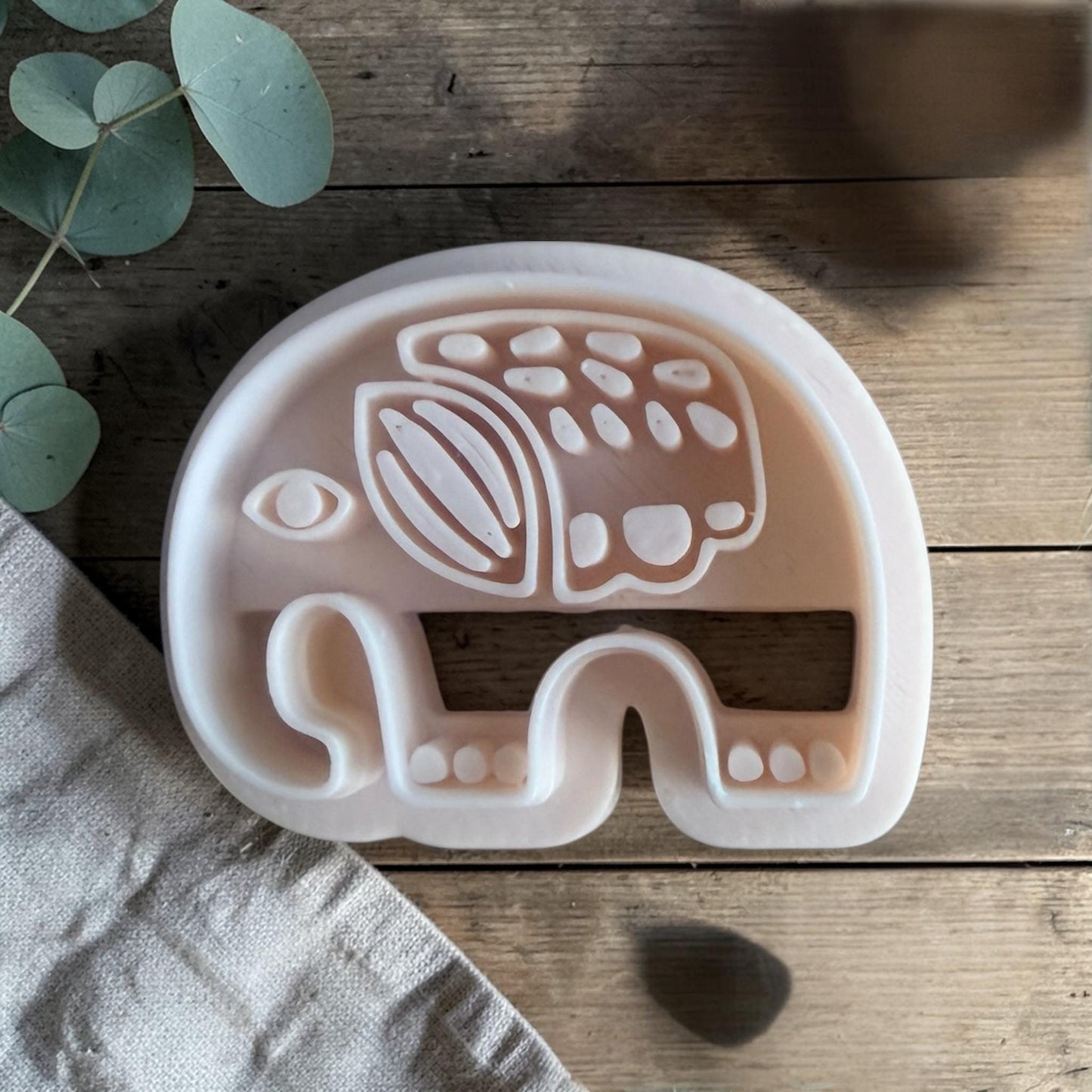 white polymer clay elephant cutter with Scandinavian folk pattern on wooden background