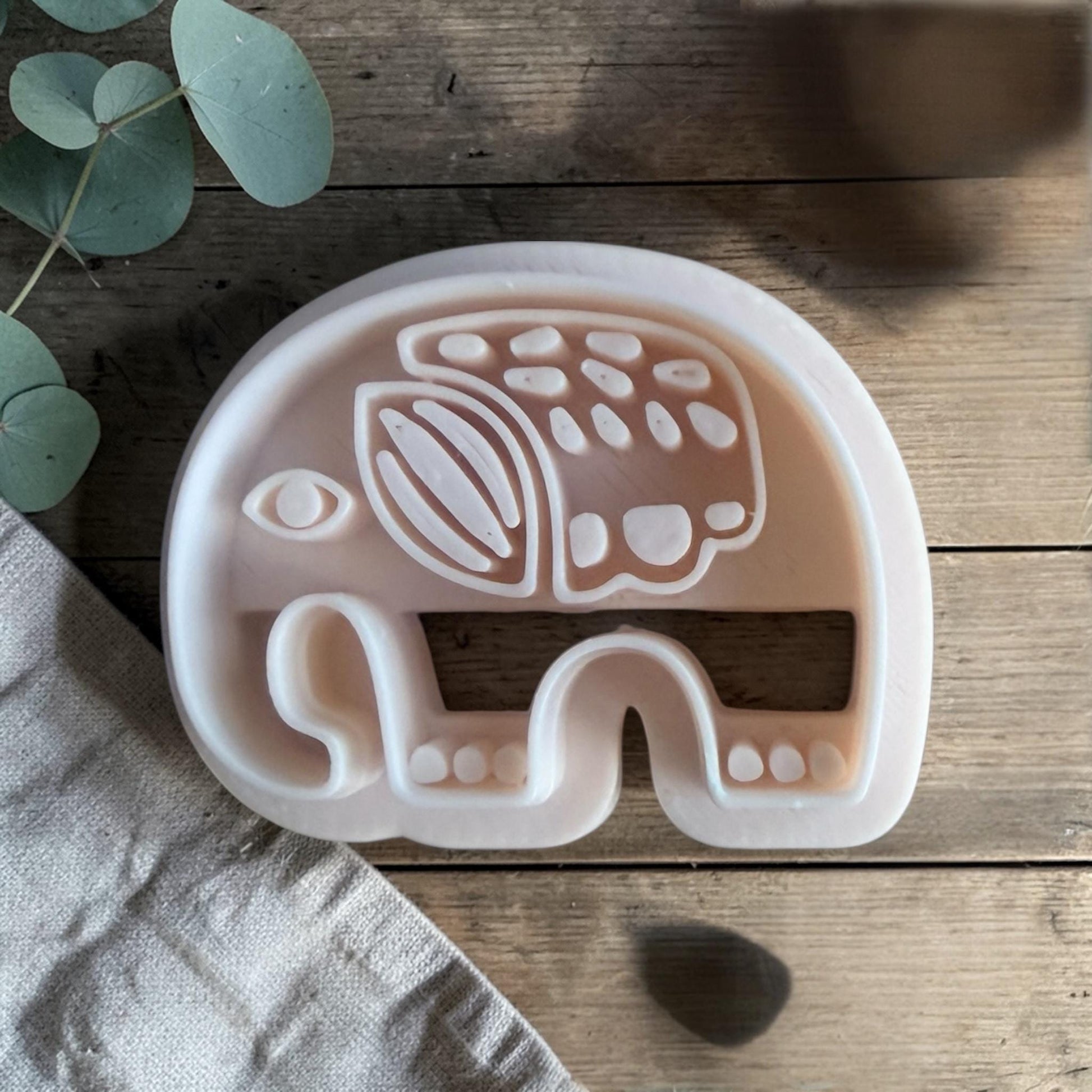 white polymer clay elephant cutter with Scandinavian folk pattern on wooden background