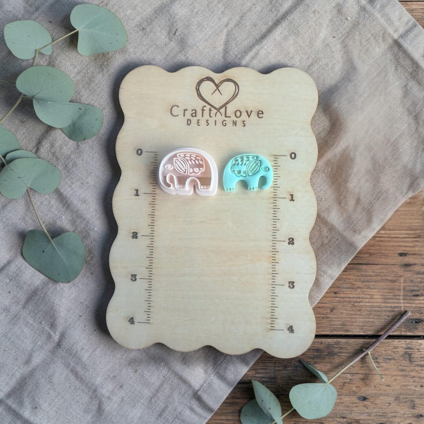 two small clay elephant charms displayed on Craft Love Designs ruler board