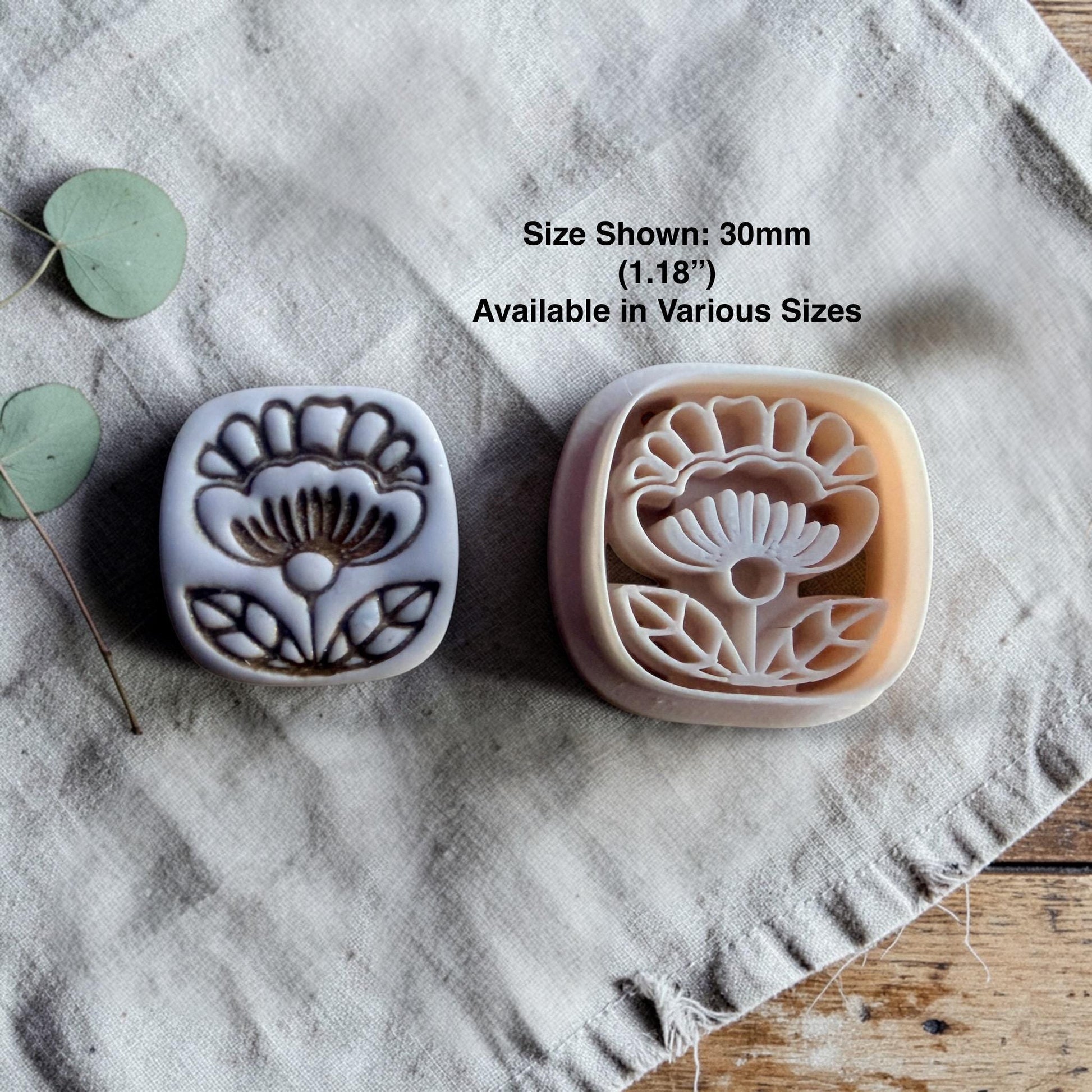 clay flower cutter and finished charm displayed with size text on linen