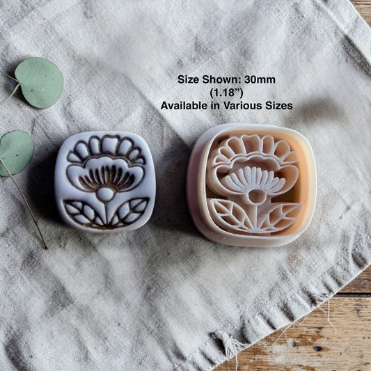 clay flower cutter and finished charm displayed with size text on linen