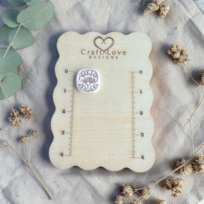 finished clay flower charm displayed on Craft Love Designs ruler board