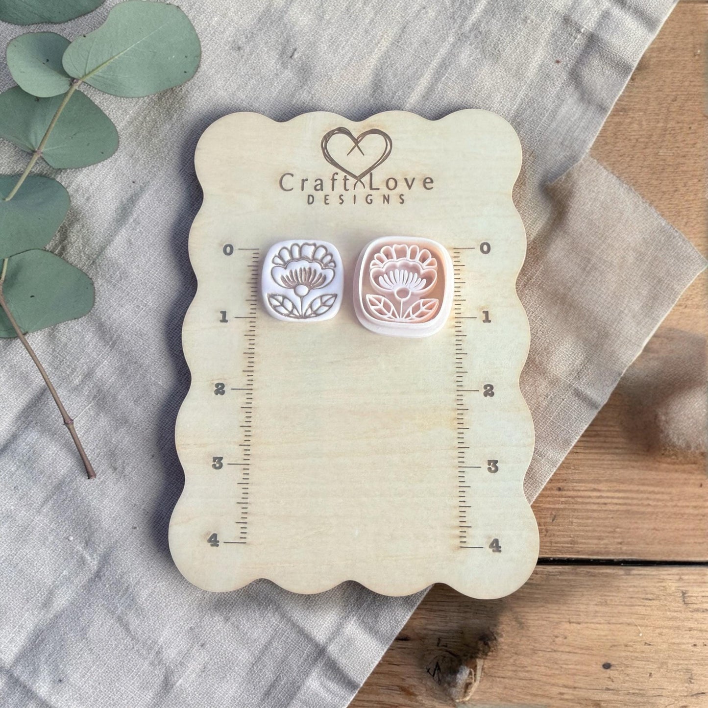 two small clay flower charms displayed on Craft Love Designs ruler board