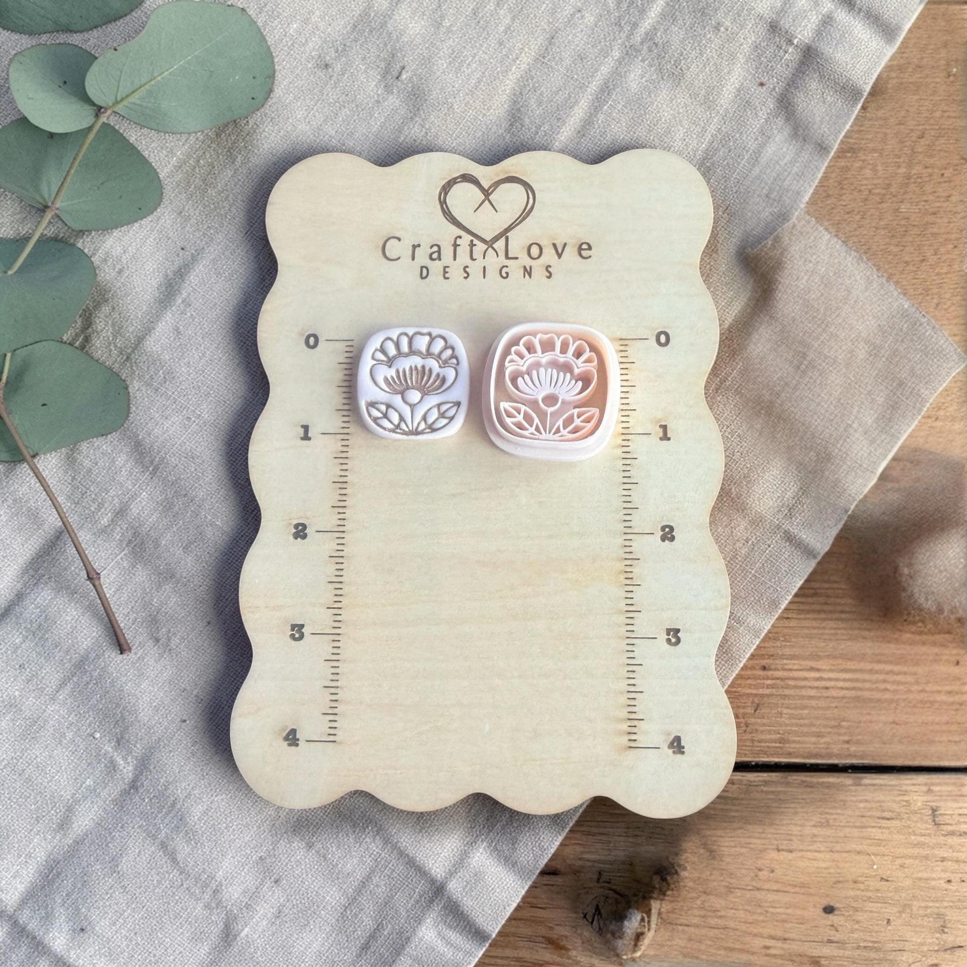 two small clay flower charms displayed on Craft Love Designs ruler board