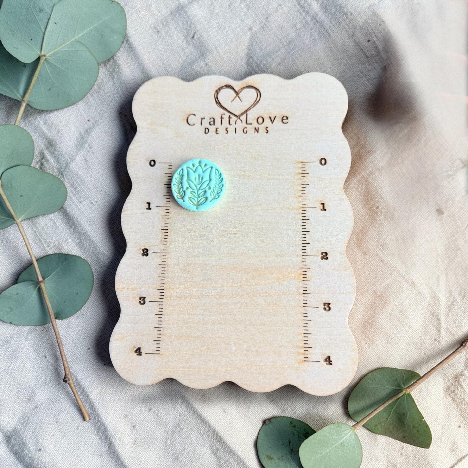turquoise embossed tulip clay charm displayed on ruler board