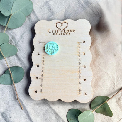turquoise embossed tulip clay charm displayed on ruler board
